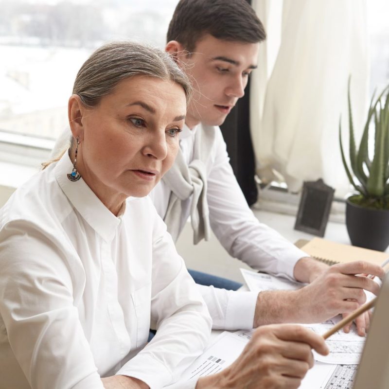 confident-skilled-mature-woman-engineer-making-sketches-using-computer-engineering-equipment-working-construction-plan-together-with-her-ambitious-young-man-colleague-talent-creativity